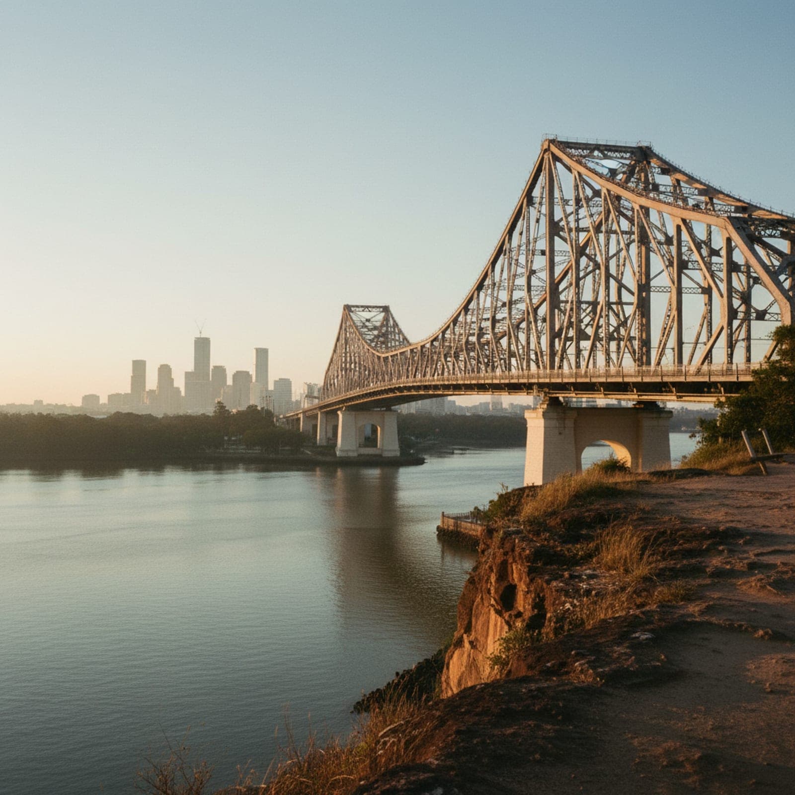 Brisbane, QLD — Story Bridge spans the Brisbane River at golden hour, CBD towers rising on the right with warm window light, the silhouette of Kangaroo Point cliffs in the midground, river surface catching the last orange glow. Side-on composition, slight elevation, no drone-HDR look.