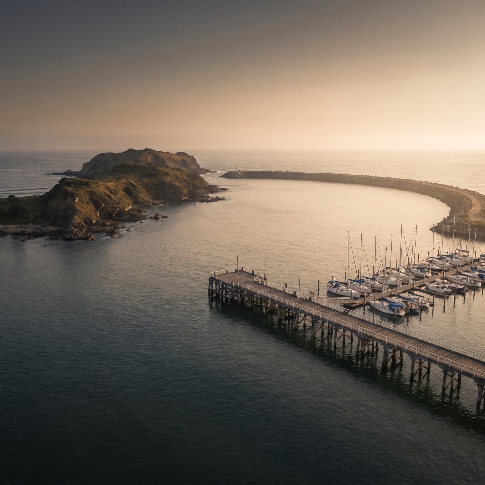 Coffs Harbour, NSW — Coffs Harbour Jetty and marina at golden hour with Muttonbird Island and the harbour breakwall framing the bay
