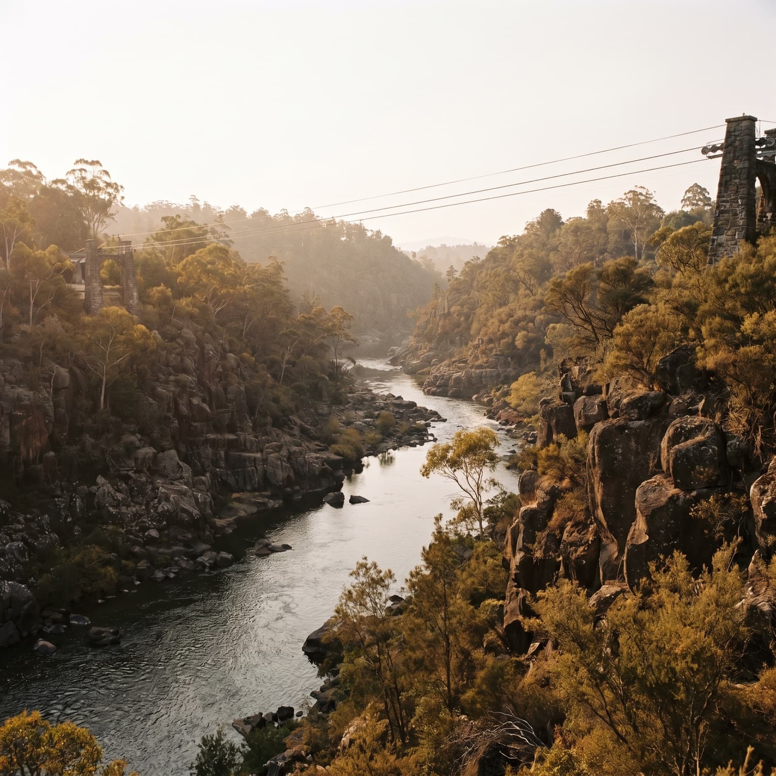 Launceston, TAS — Cataract Gorge in early autumn, the basin and the chairlift cables above the South Esk, dolerite cliffs and gum trees, low warm light, restrained and editorial.