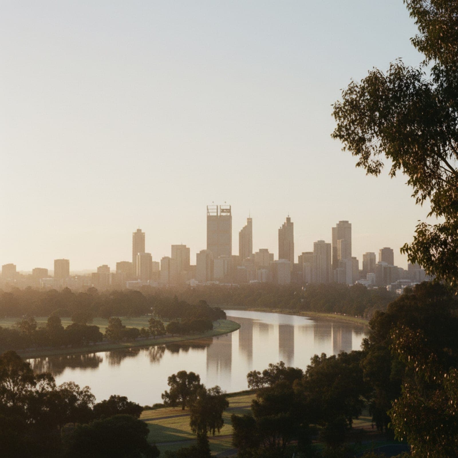 Perth, WA — The Swan River from Kings Park overlook at twilight, Perth CBD towers across the water in soft purple-blue light, Narrows Bridge curving across the bottom third, a single small boat tracking across the river surface. Cool palette, restrained, no garish sunset.